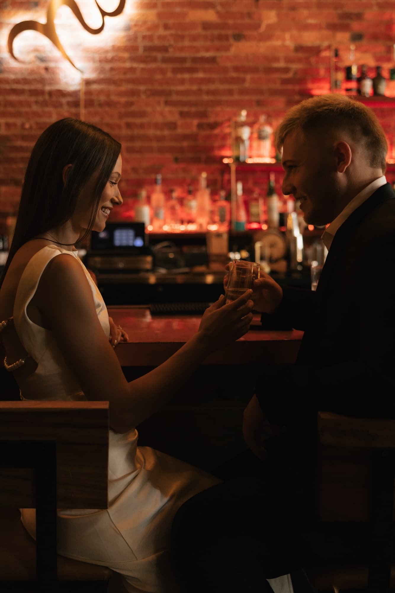 Andrew and Madeline sharing a drink together at a warmly lit bar